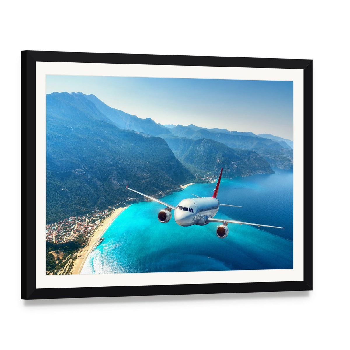 Commercial Airplane Over Ocean Coastline Canvas Wall Art, framed print with white mat and black frame, angled product view