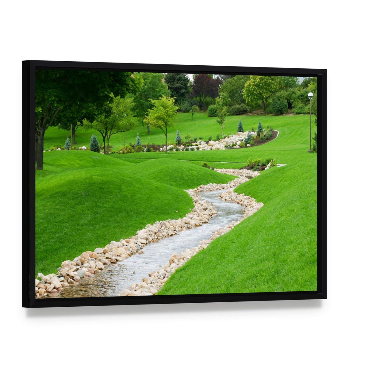 Stream Flowing Through Grassy Hills with Trees Canvas Wall Art, framed canvas in a black floater frame, angled product view