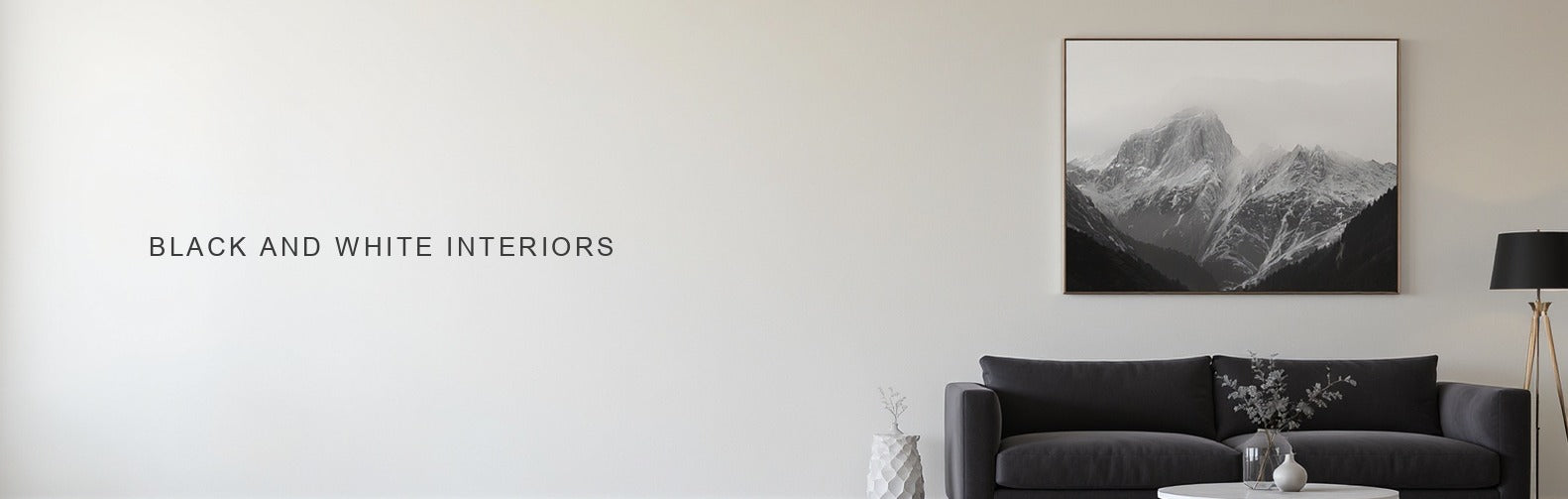 Black and white interior: a monochrome mountain canvas above a charcoal sofa and marble table