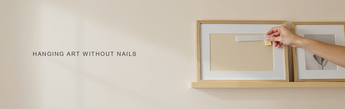 Hanging art without nails: an adhesive strip on a light frame beside a picture ledge with leaning prints