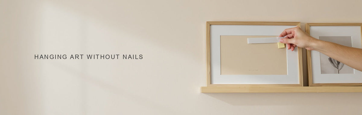 How to hang wall art without nails: an adhesive strip on a light frame beside a picture ledge with leaning prints