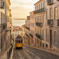 Lisbon Wall Art canvas print, pastel tiled facades on a steep street with a yellow tram climbing and the river below