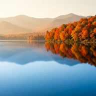 Lake Champlain Wall Art canvas print, still blue water with the Adirondack ridges beyond and a shoreline of blazing autumn
