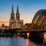 Cologne Wall Art canvas print, the twin gothic spires of the cathedral above the Rhine and the arched railway bridge at dusk