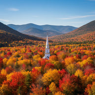 Vermont Wall Art canvas print, a white church steeple in a valley of blazing autumn maples with green mountains beyond