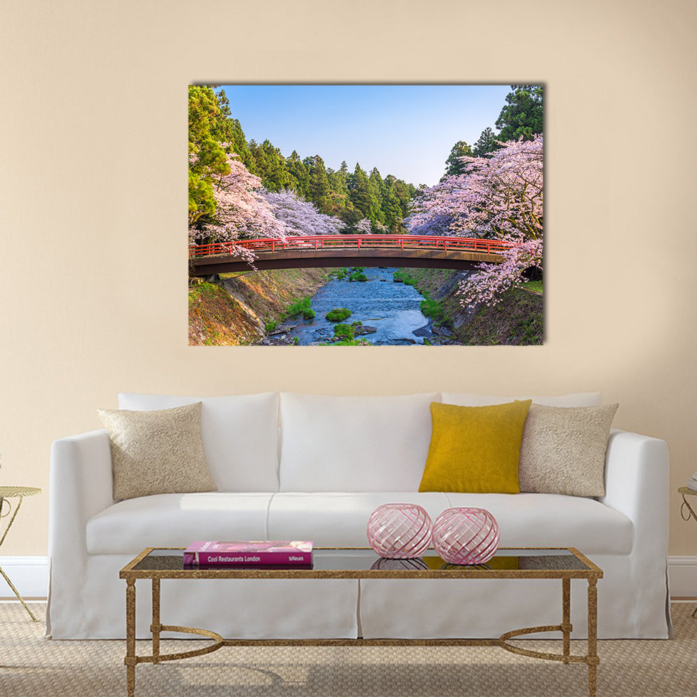 Cherry Blossoms Over Red Arched Bridge Canvas Wall Art in green, blue and pink, single panel hung on a wall
