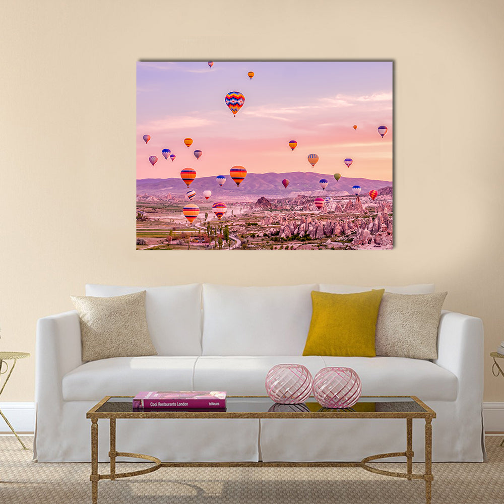 Hot Air balloons Flying Over Rock Landscape At Cappadocia Canvas Wall Art in orange, purple and pink, single panel hung on a wall