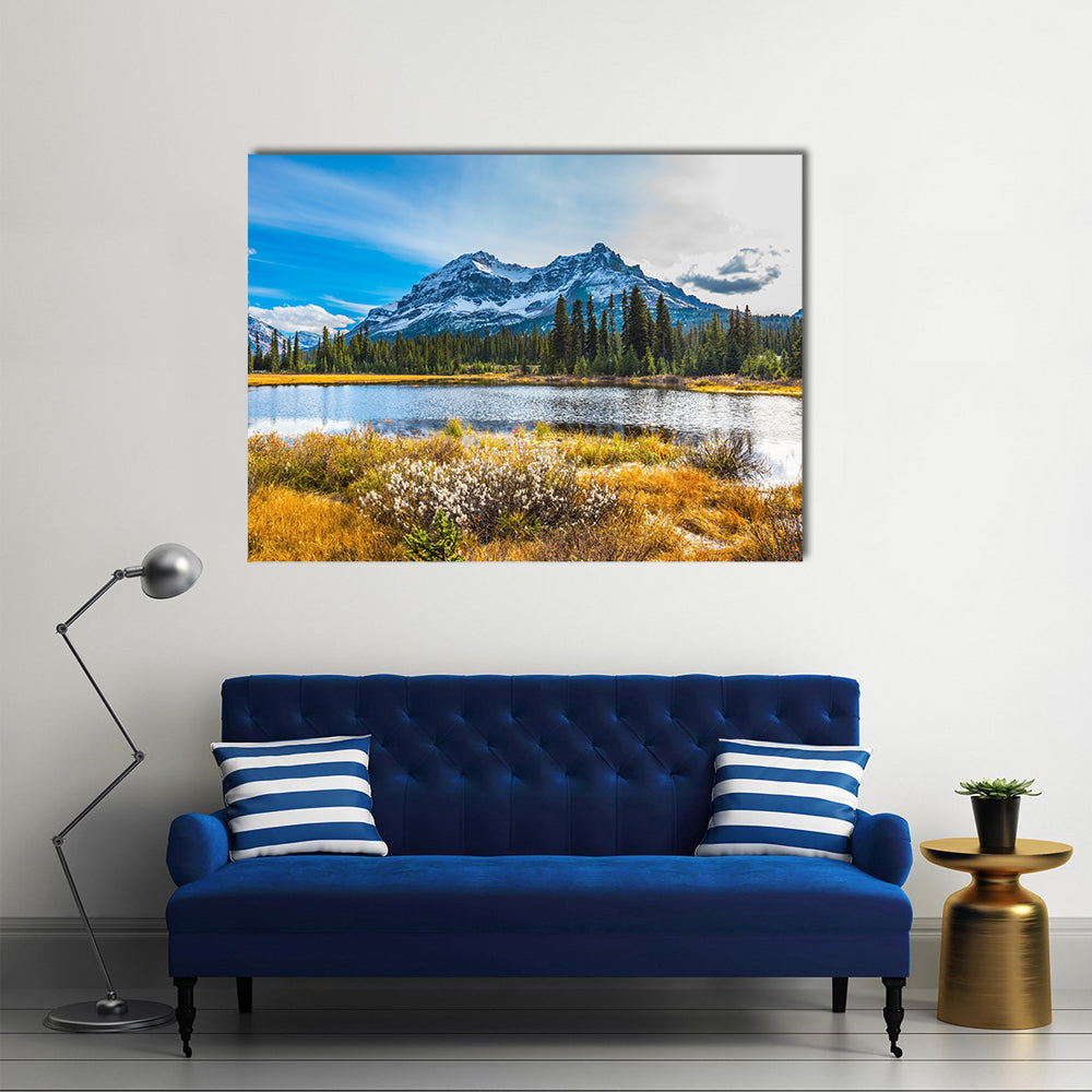 Snowy Rocky Mountains Lake Reflection Canvas Wall Art in yellow, green and blue, single panel hung on a wall