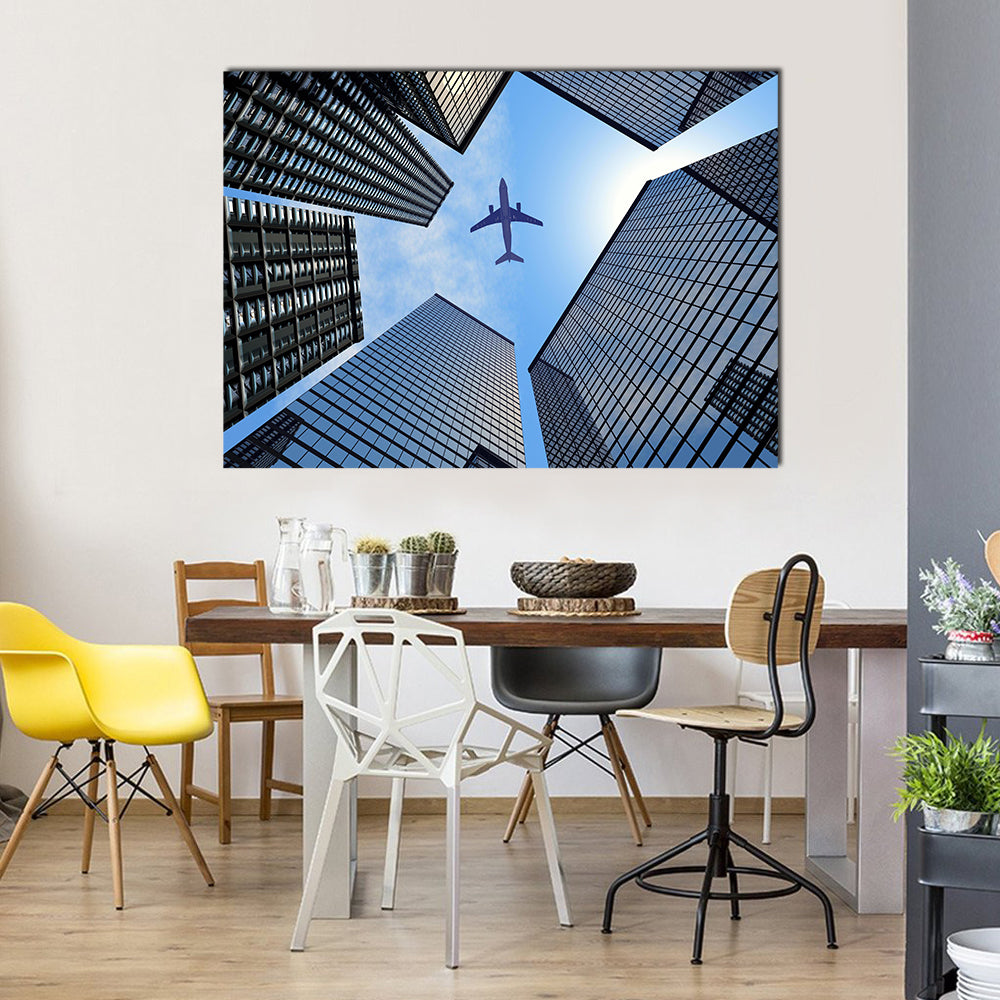 Airplane Above Buildings Canvas Wall Art