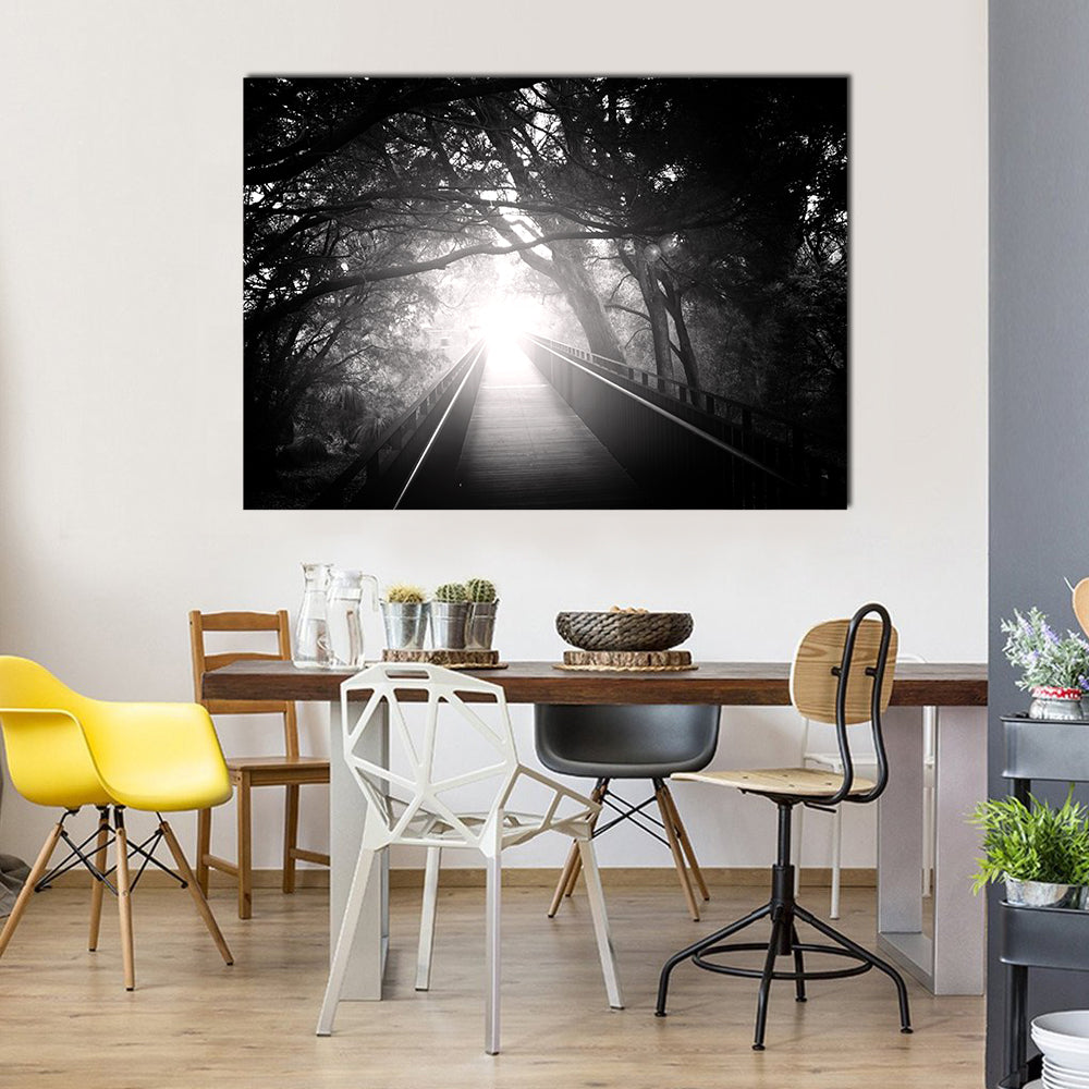 Wooden Bridge Into Sunlit Forest Canvas Wall Art in black, white and gray, single panel hung on a wall