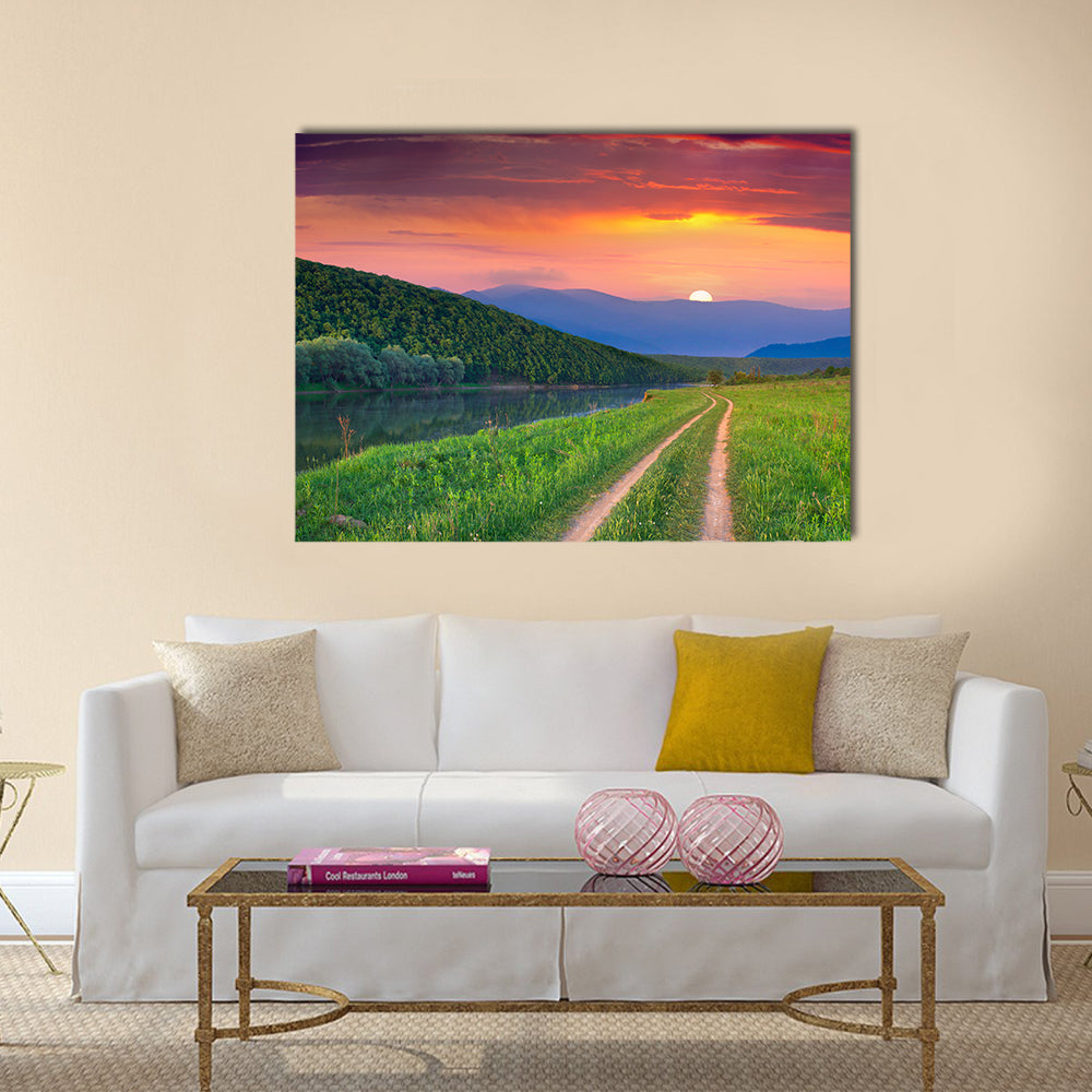 Sunset Meadow with River and Dirt Road Canvas Wall Art in orange, green and purple, single panel hung on a wall