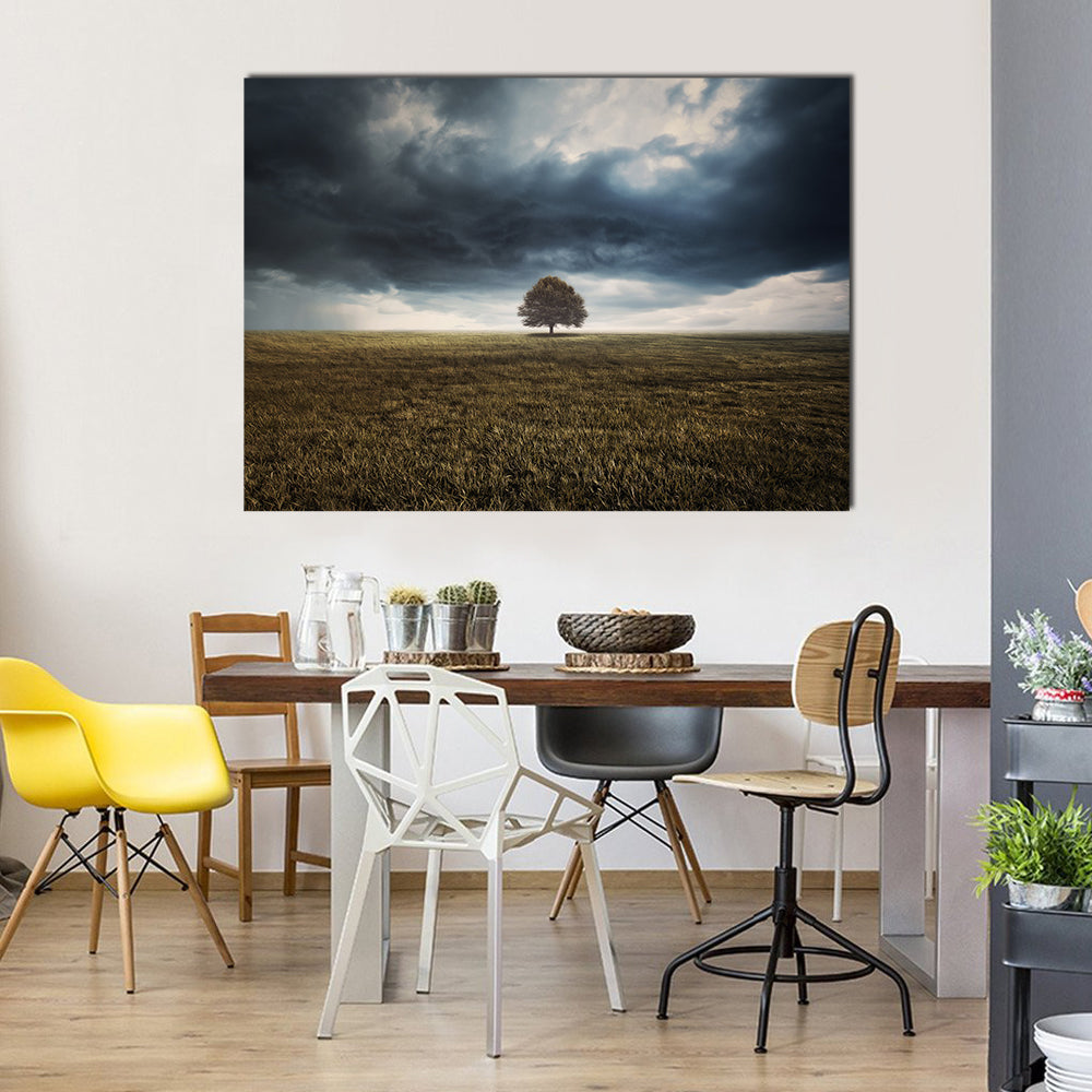 Tree in Field Under Storm Clouds Canvas Wall Art in gray, brown and blue, single panel hung on a wall