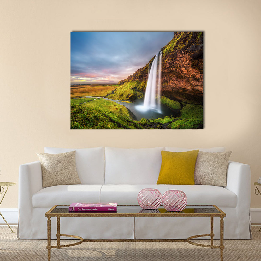 Seljalandsfoss Waterfall At Sunset In Iceland Canvas Wall Art in orange, green and blue, single panel hung on a wall