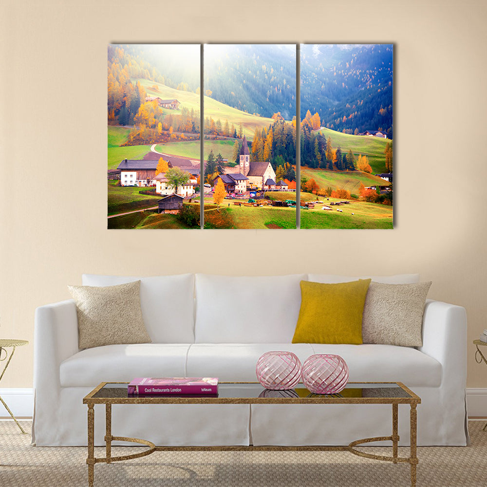 Santa Maddalena Village at Sunrise Canvas Wall Art in orange, yellow and green, 3 panel horizontal set hung on a wall