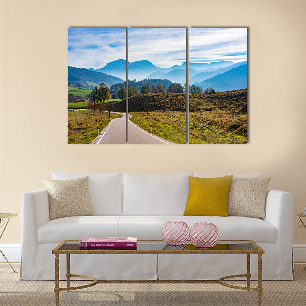 Winding Road in the Bavarian Alps Canvas Wall Art in brown, green and blue, 3 panel horizontal set hung on a wall