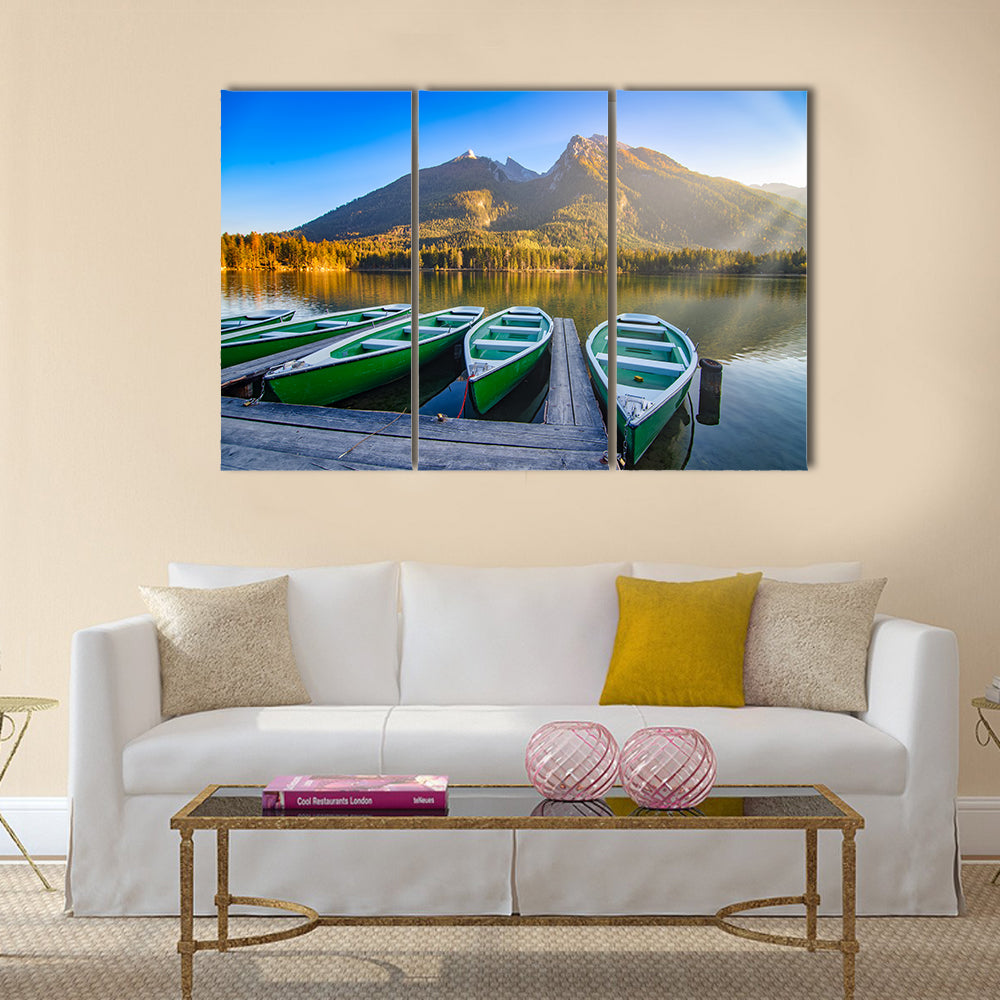 Green Rowboats on Mountain Lake Canvas Wall Art in brown, green and blue, 3 panel horizontal set hung on a wall