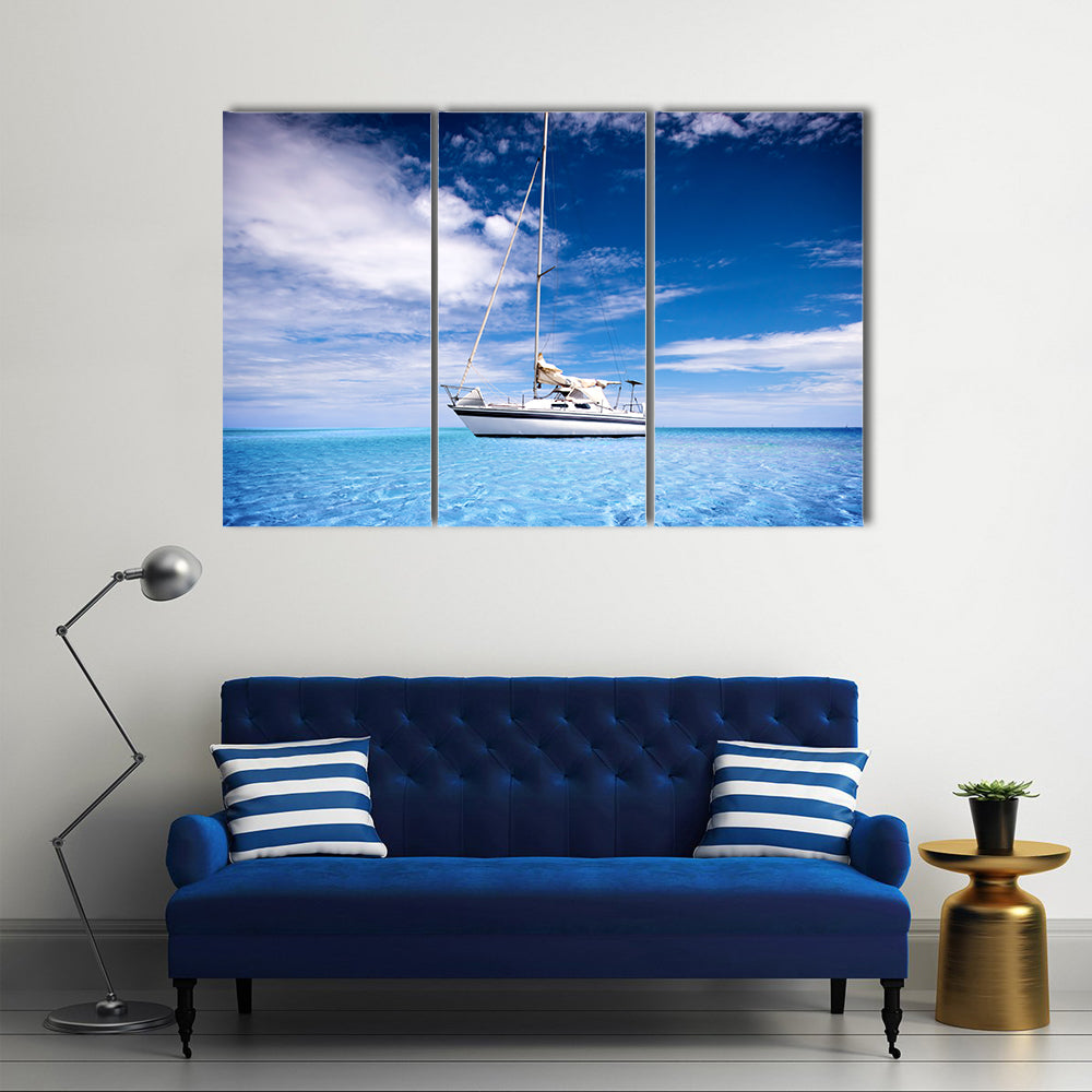 Single-masted White Sailboat on Turquoise Water Canvas Wall Art in white and blue, 3 panel horizontal set hung on a wall