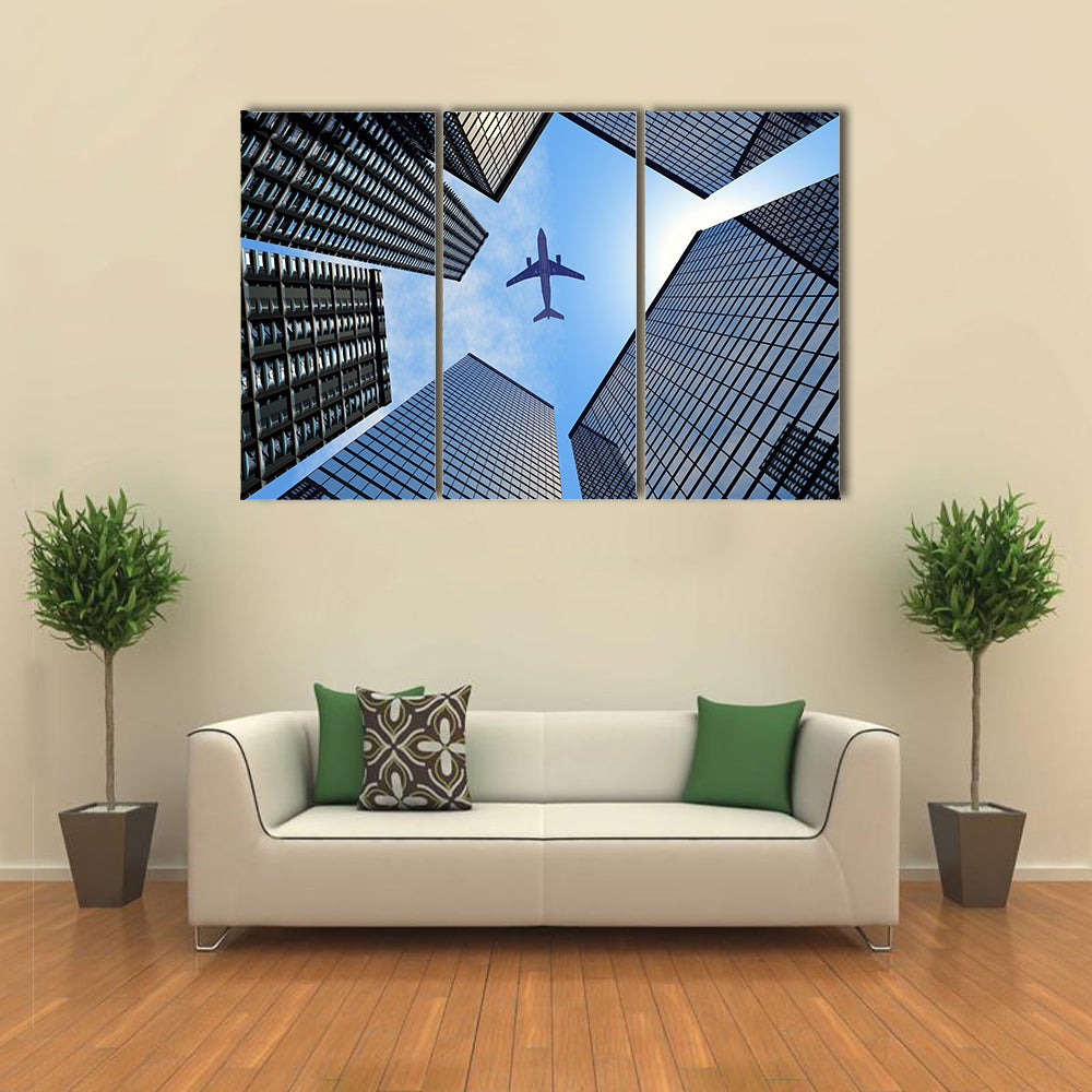 Airplane Above Buildings Canvas Wall Art