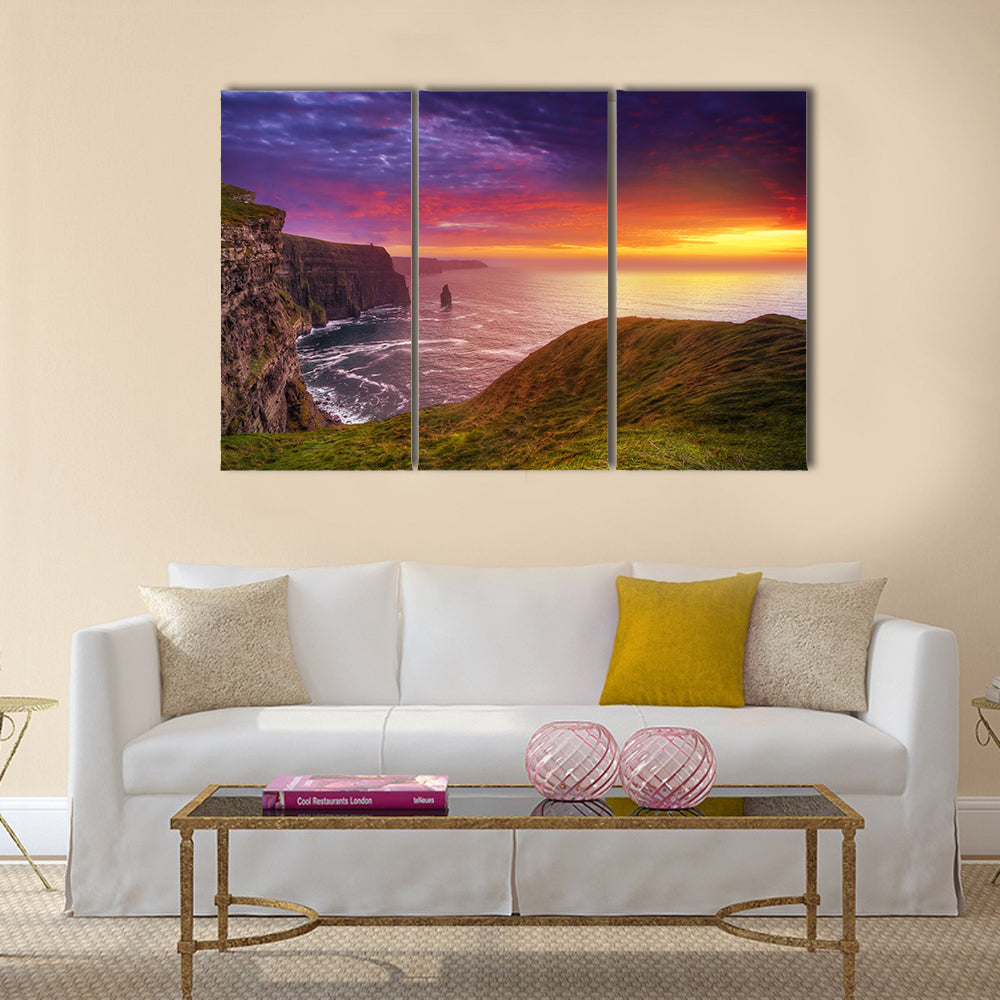 Sunset at the Cliffs of Moher Canvas Wall Art in orange, green and purple, 3 panel horizontal set hung on a wall