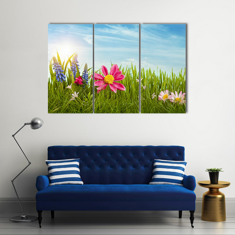 Spring Flowers Under Blue Sky Canvas Wall Art in green, blue and pink, 3 panel horizontal set hung on a wall
