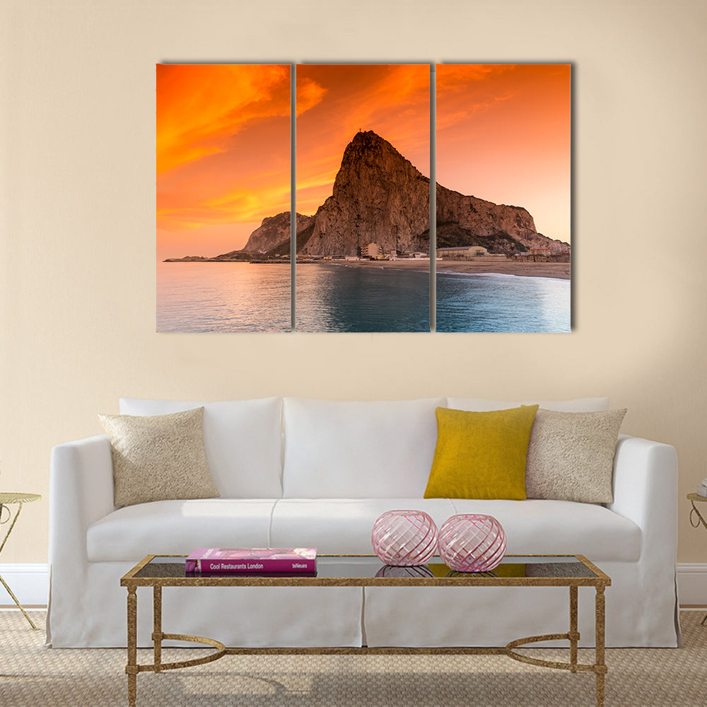 Rock of Gibraltar at Sunset Canvas Wall Art in brown, orange and blue, 3 panel horizontal set hung on a wall