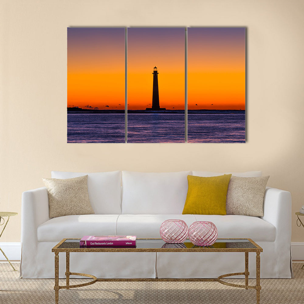 Morris Island Lighthouse at Sunset Canvas Wall Art in orange, blue and purple, 3 panel horizontal set hung on a wall