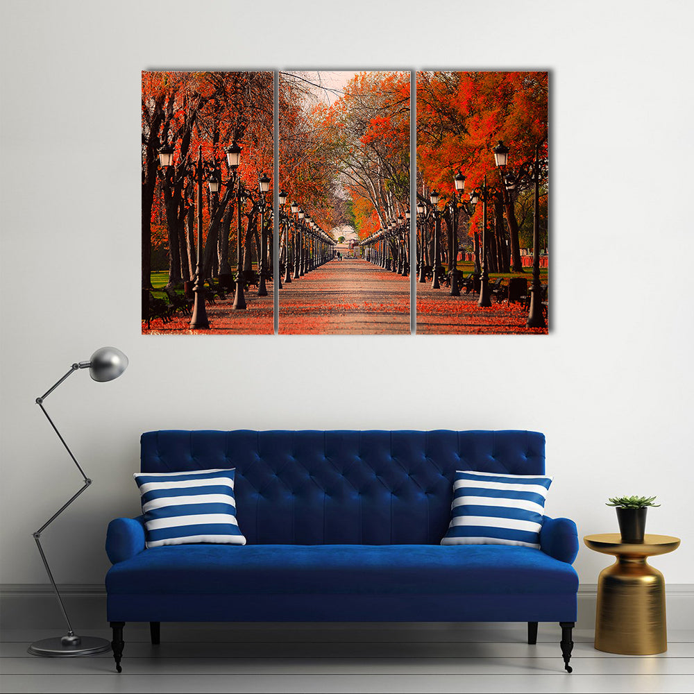 Red Autumn Park Pathway Canvas Wall Art in brown, red and orange, 3 panel horizontal set hung on a wall