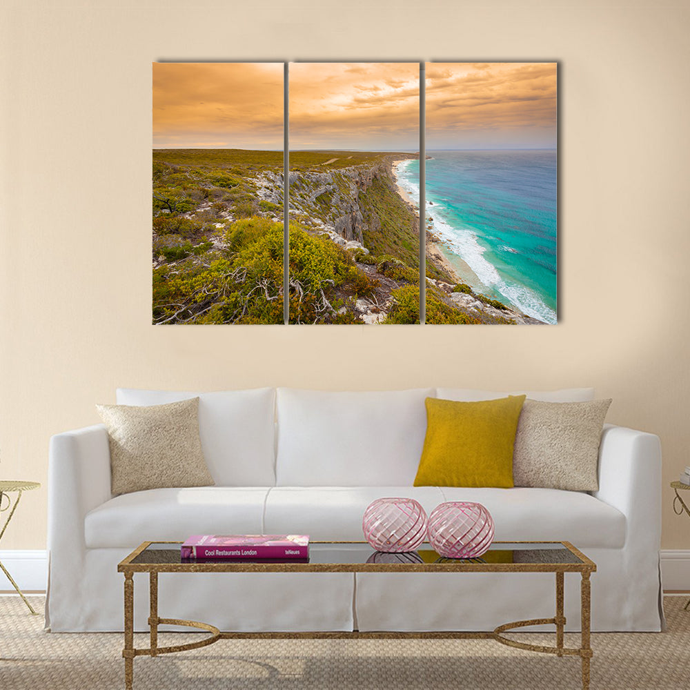 Kangaroo Island Cliffs and Turquoise Sea at Sunset Canvas Wall Art in orange, green and blue, 3 panel horizontal set hung on a wall