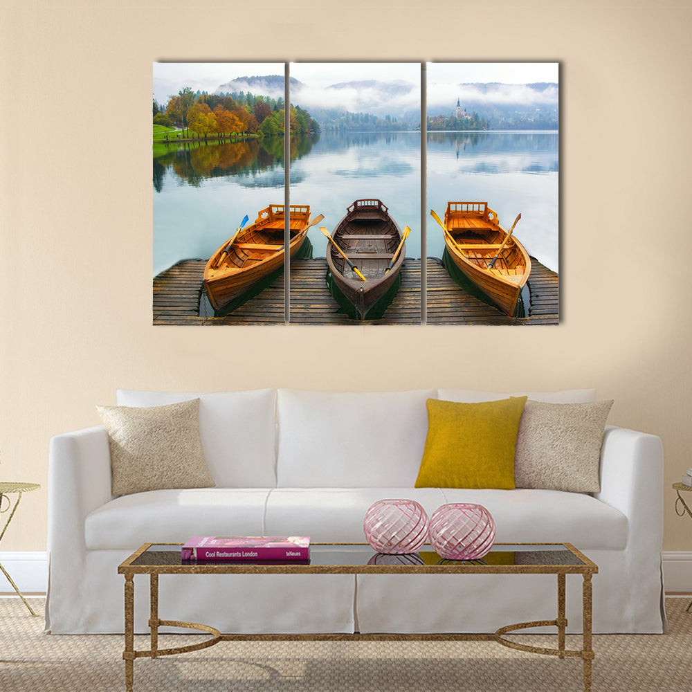 Boats on Bled Lake Canvas Wall Art in gray, brown and blue, 3 panel horizontal set hung on a wall