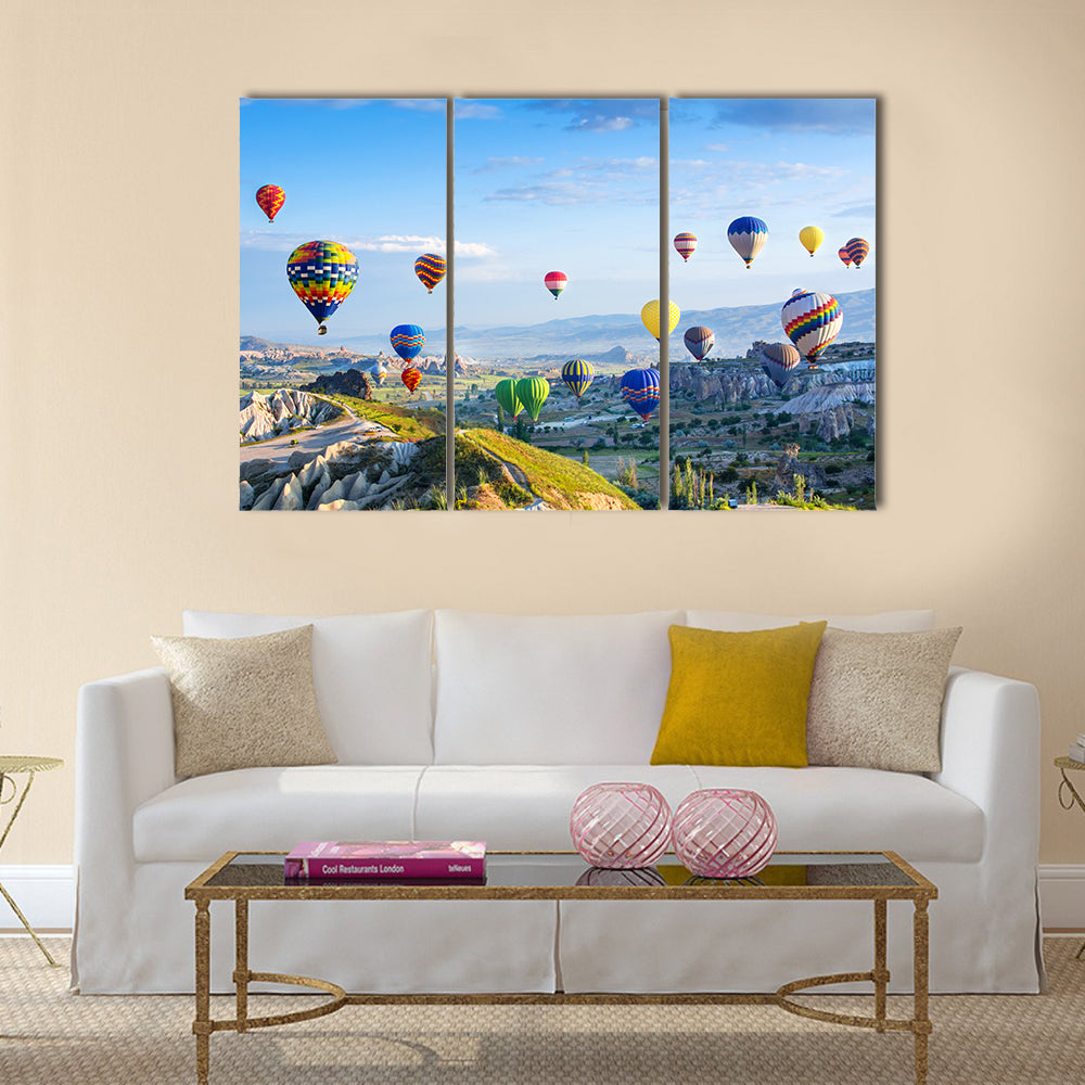 Hot Air Balloons Over Cappadocia Canvas Wall Art in blue and multicolor, 3 panel horizontal set hung on a wall