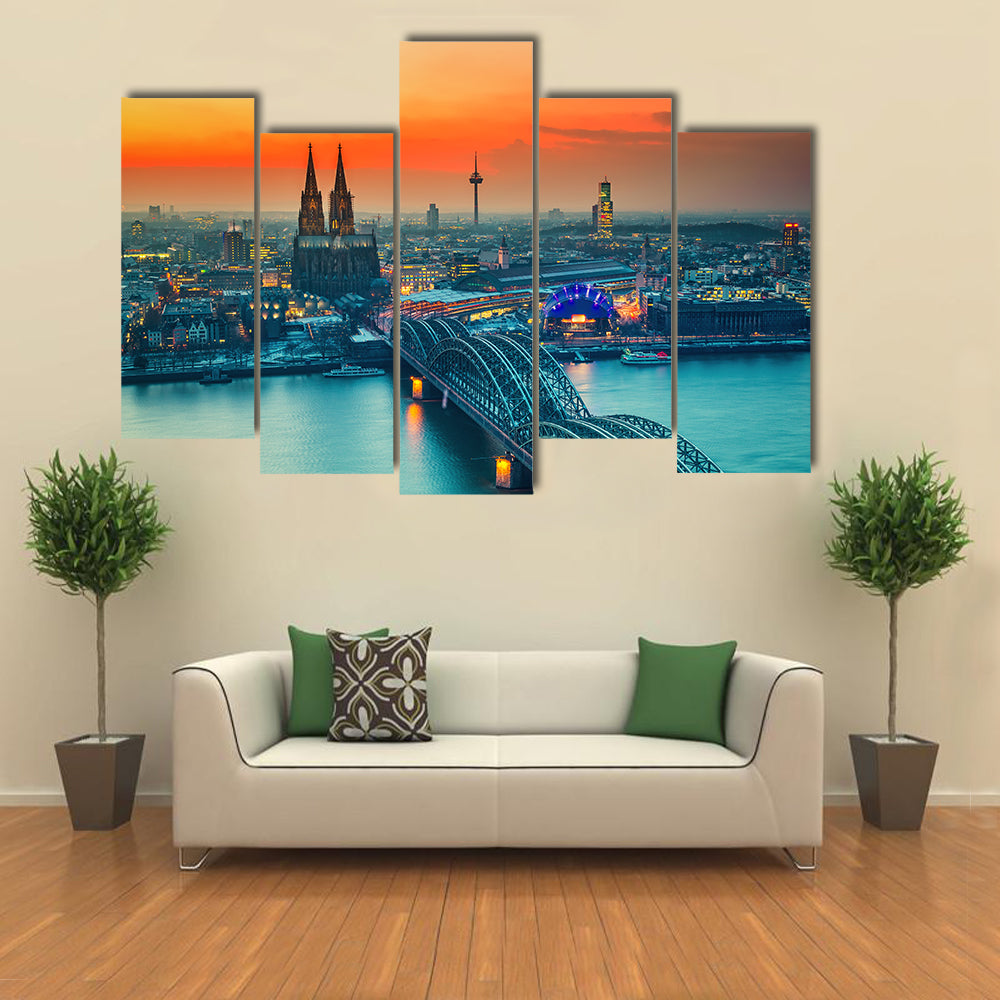 Cologne Cathedral And Hohenzollern Bridge At Night In Germany Canvas Wall Art in gray, orange and yellow, 5 panel Pop layout hung on a wall