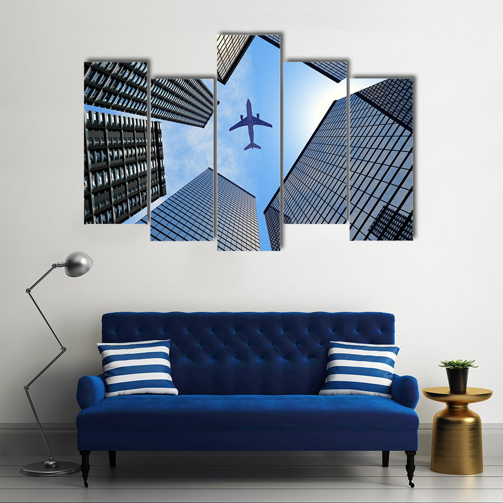 Airplane Above Buildings Canvas Wall Art