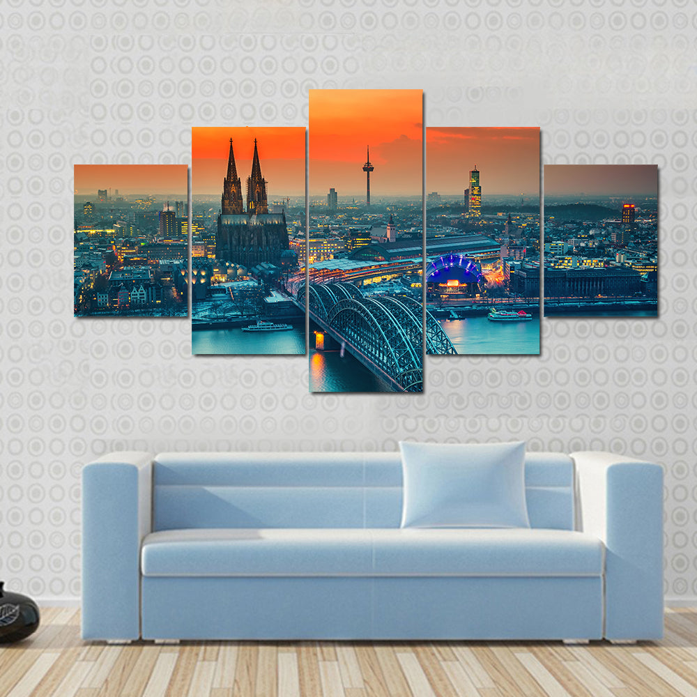 Cologne Cathedral And Hohenzollern Bridge At Night In Germany Canvas Wall Art in gray, orange and yellow, 5 panel Star layout hung on a wall