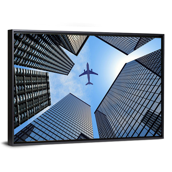 Airplane Above Buildings Canvas Wall Art