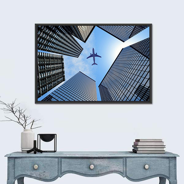 Airplane Above Buildings Canvas Wall Art