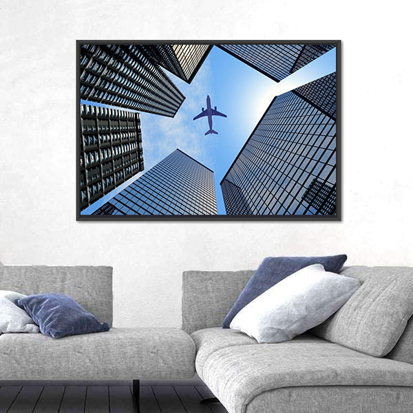 Airplane Above Buildings Canvas Wall Art