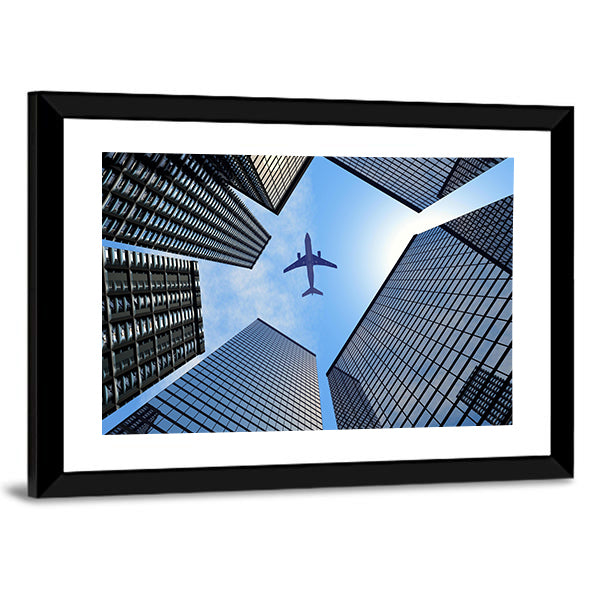 Airplane Above Buildings Canvas Wall Art