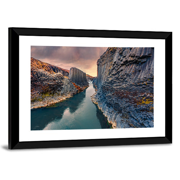 Studlagil Canyon In Iceland Canvas Wall Art in gray, orange and blue, framed print shown in a room