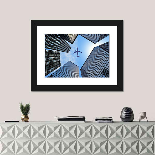 Airplane Above Buildings Canvas Wall Art
