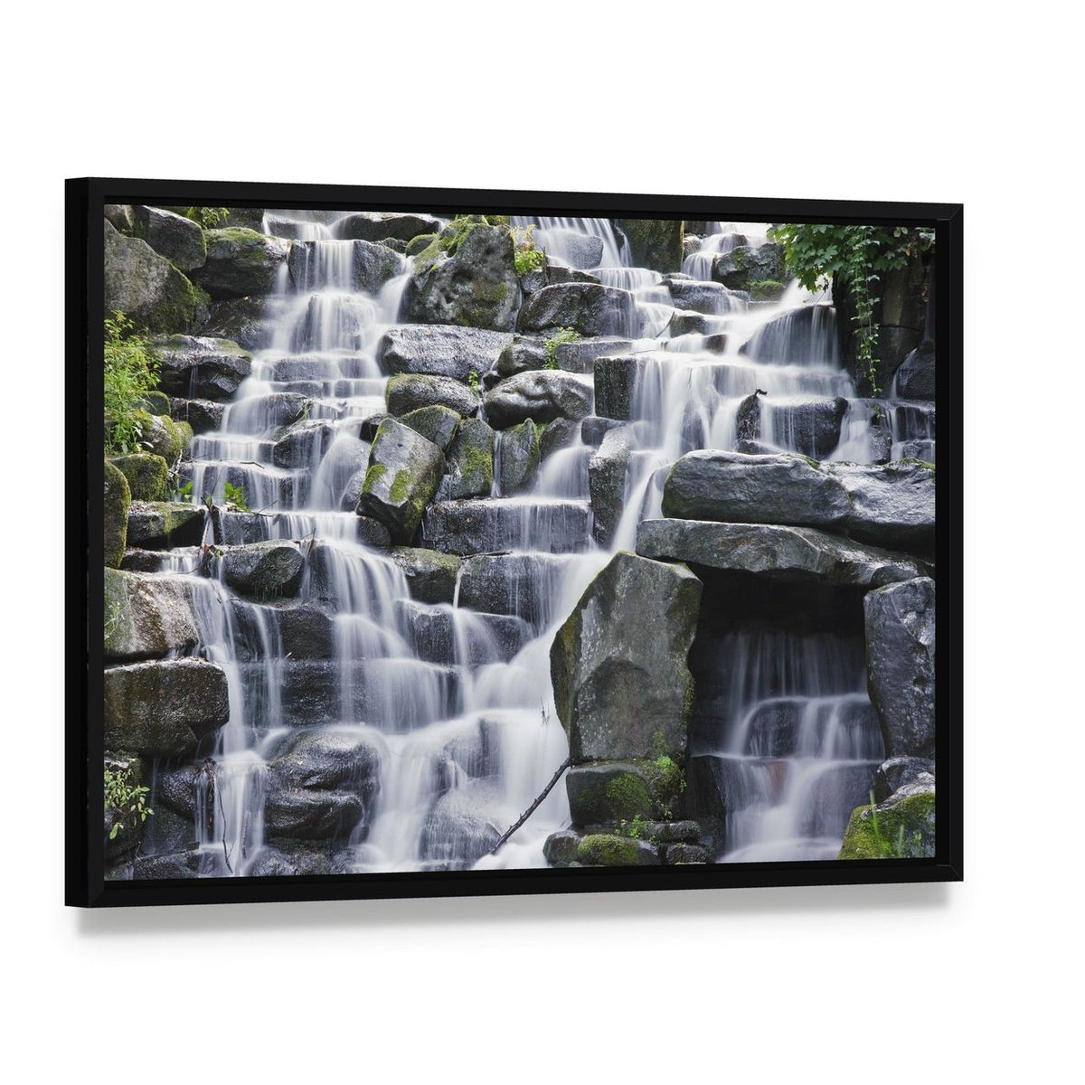 Waterfall Cascades Over Mossy Rocks Canvas Wall Art, framed canvas in a black floater frame, angled product view