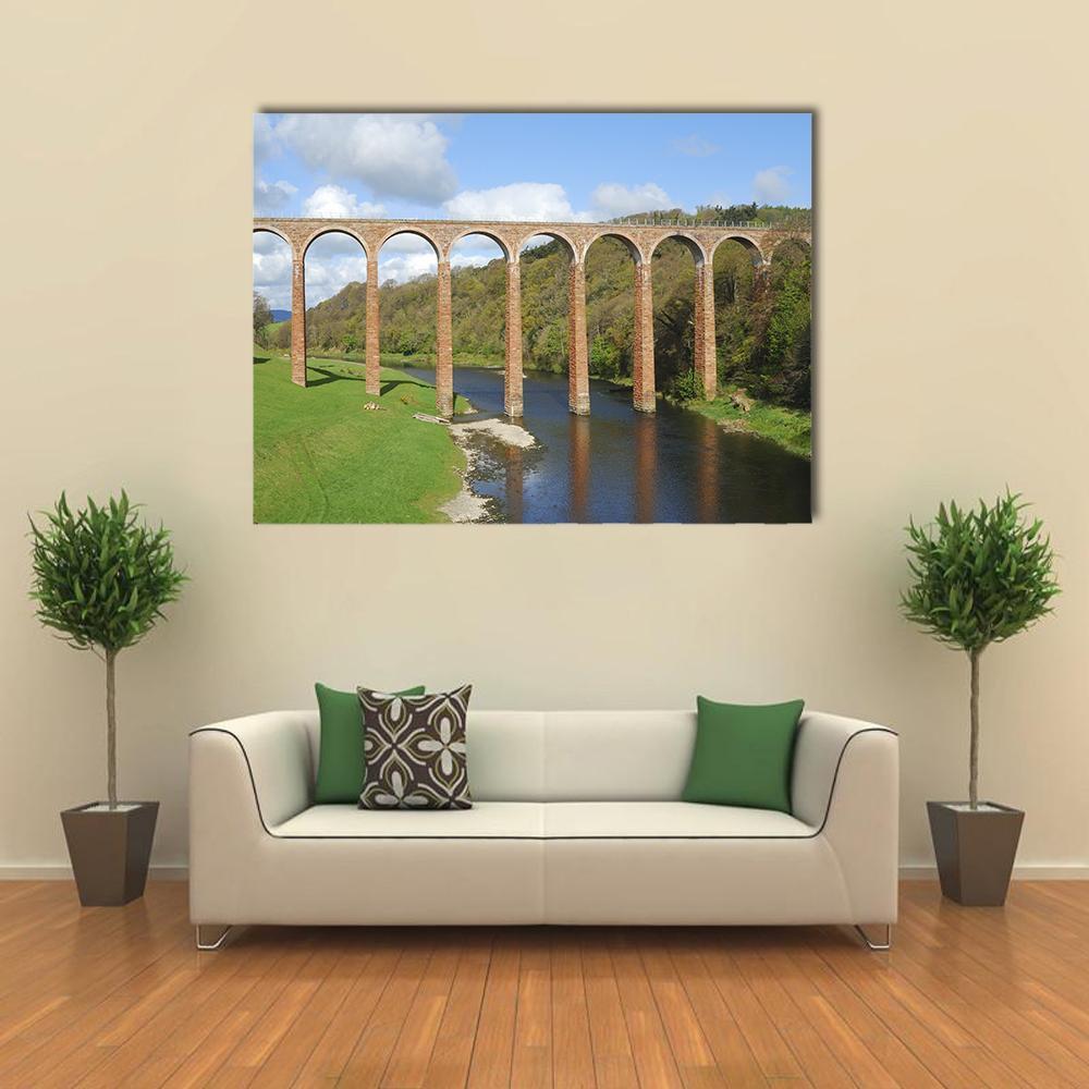 Old Stone Arch Bridge Over River Canvas Wall Art in brown, green and blue, single panel hung on a wall