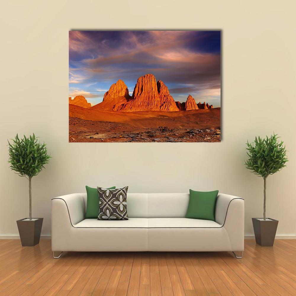 Desert Sunset Over Rock Formations Canvas Wall Art in brown, orange and blue, single panel hung on a wall