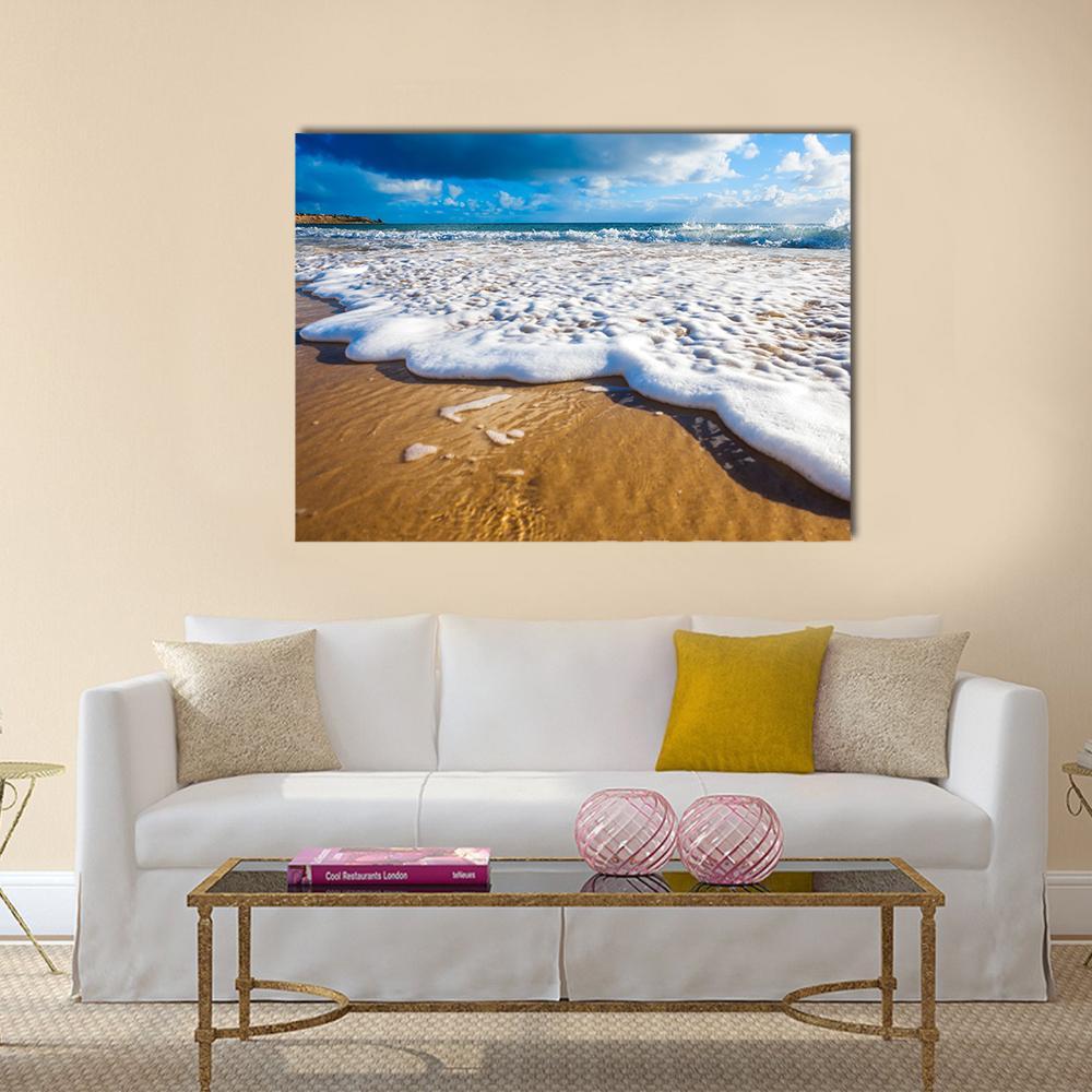 Waves Washing Over Golden Sand Canvas Wall Art in white, gold and blue, single panel hung on a wall