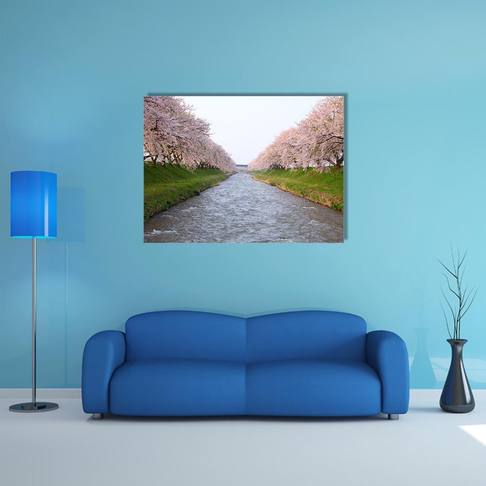 Cherry Blossom River Scene Canvas Wall Art in gray, green and pink, single panel hung on a wall