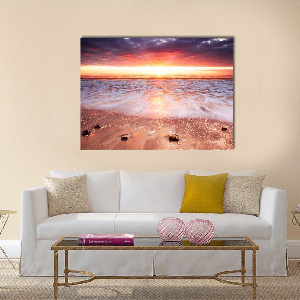Sunset Over Surf and Wet Sand Canvas Wall Art in orange, blue and purple, single panel hung on a wall