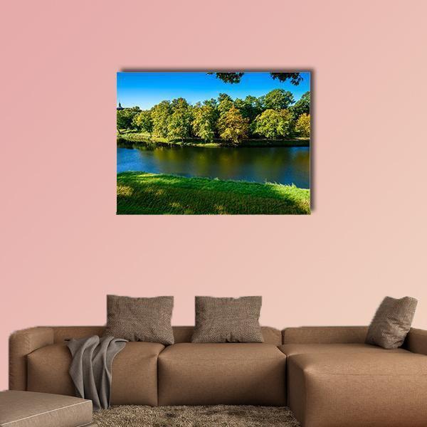 Autumn Riverbank Reflections Canvas Wall Art in yellow, green and blue, single panel hung on a wall