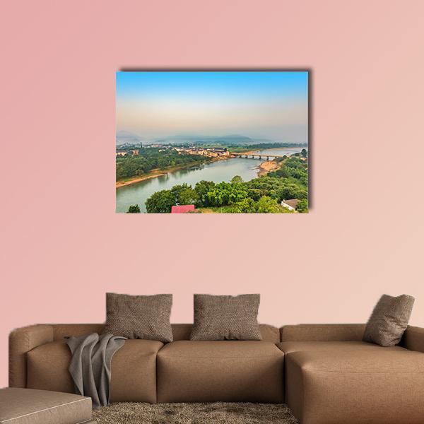 Bridge Over Winding River at Dawn Canvas Wall Art in orange, green and blue, single panel hung on a wall