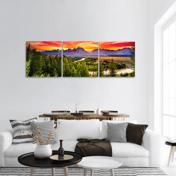 Snake River Sunset Over Snow-dusted Peaks Panoramic Canvas Wall Art in orange, green and purple, hung on a wall