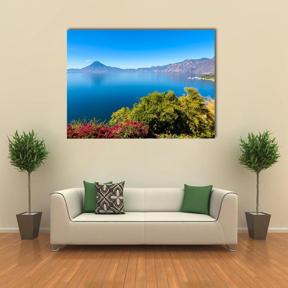 Clear Blue Lake with Volcanoes Canvas Wall Art in green and blue, single panel hung on a wall