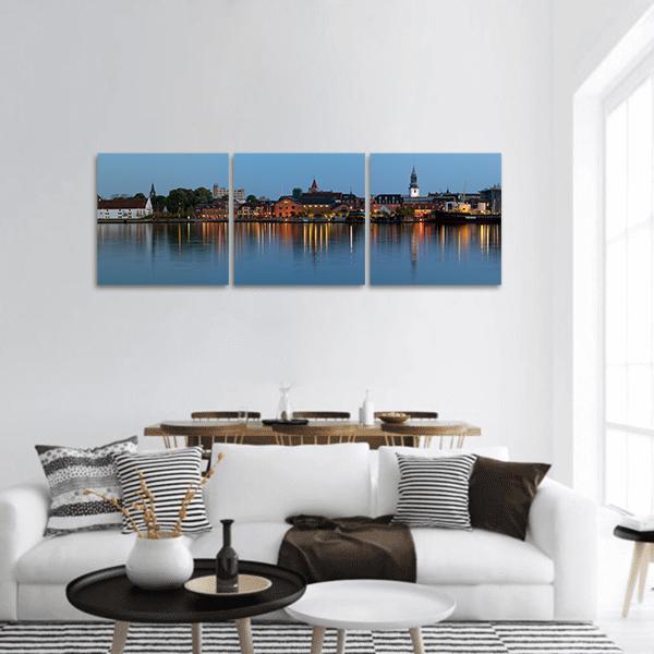 Aalborg Night Skyline with Water Reflections Panoramic Canvas Wall Art in black, blue and navy, hung on a wall
